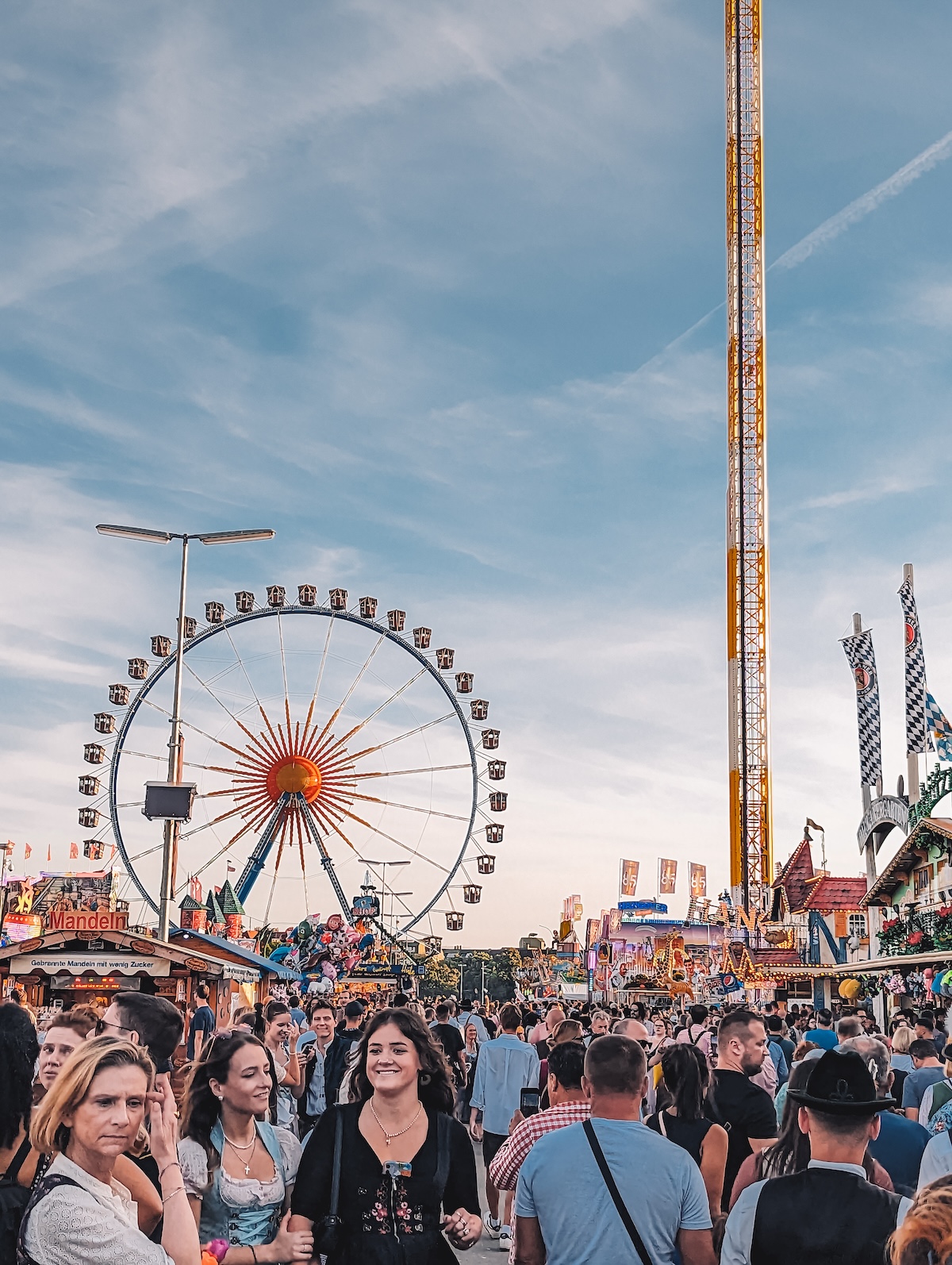 Busy street at Oktoberfest, with fair rides in background