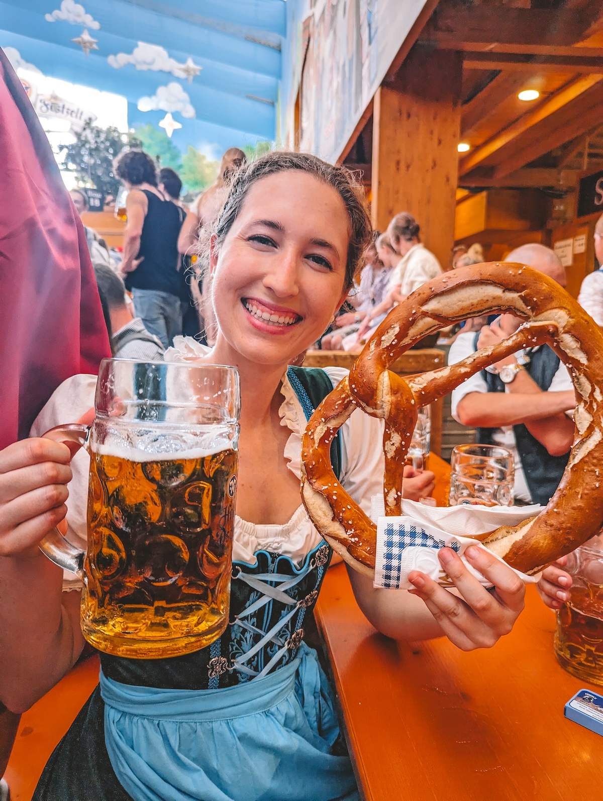 Woman holding beer and pretzel at Oktoberfest