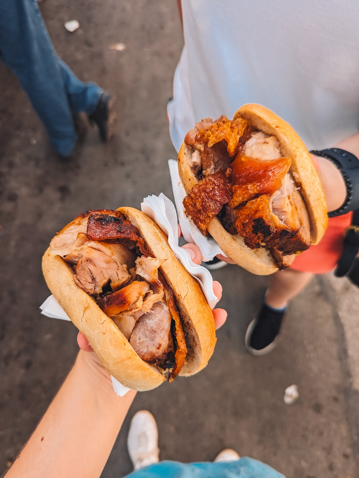 Two pork sandwiches held aloft