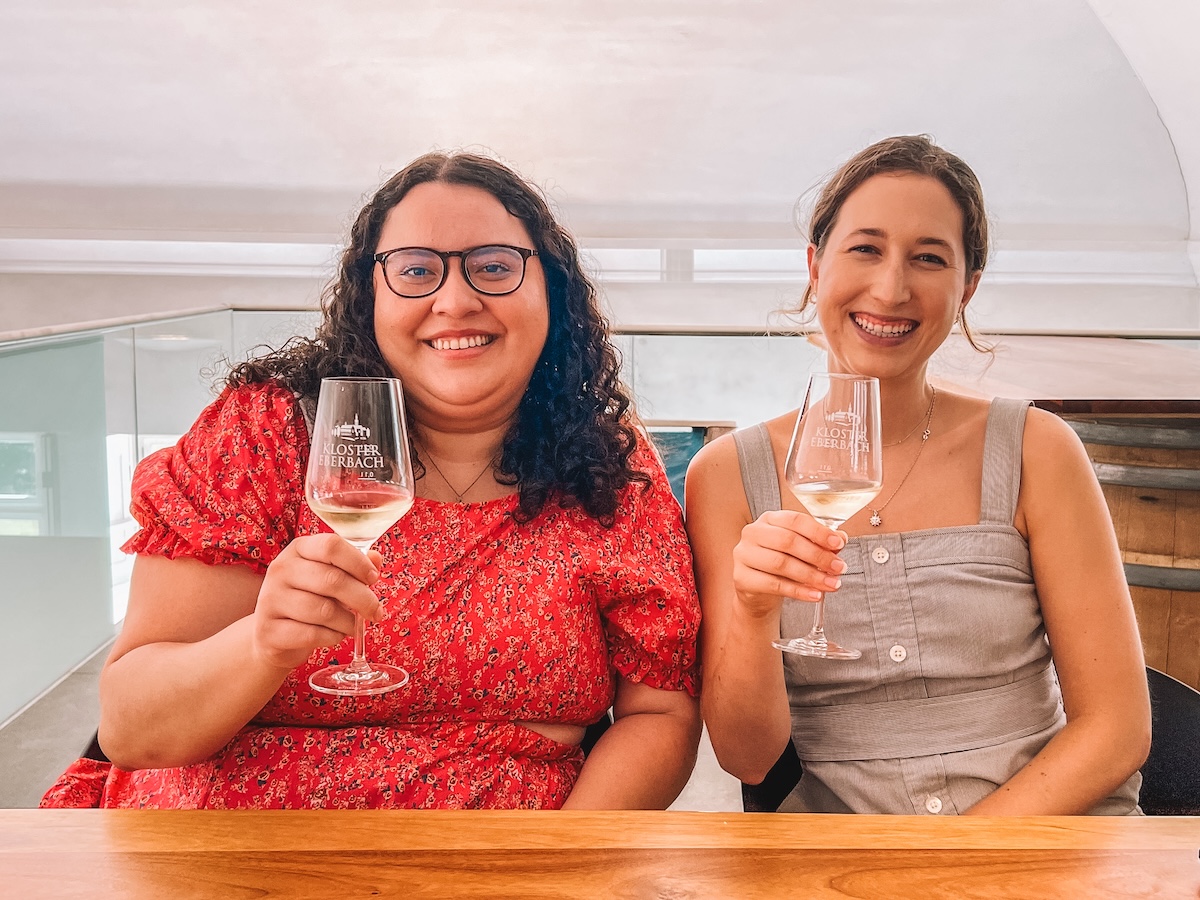 Two women smiling with wine glasses held aloft.