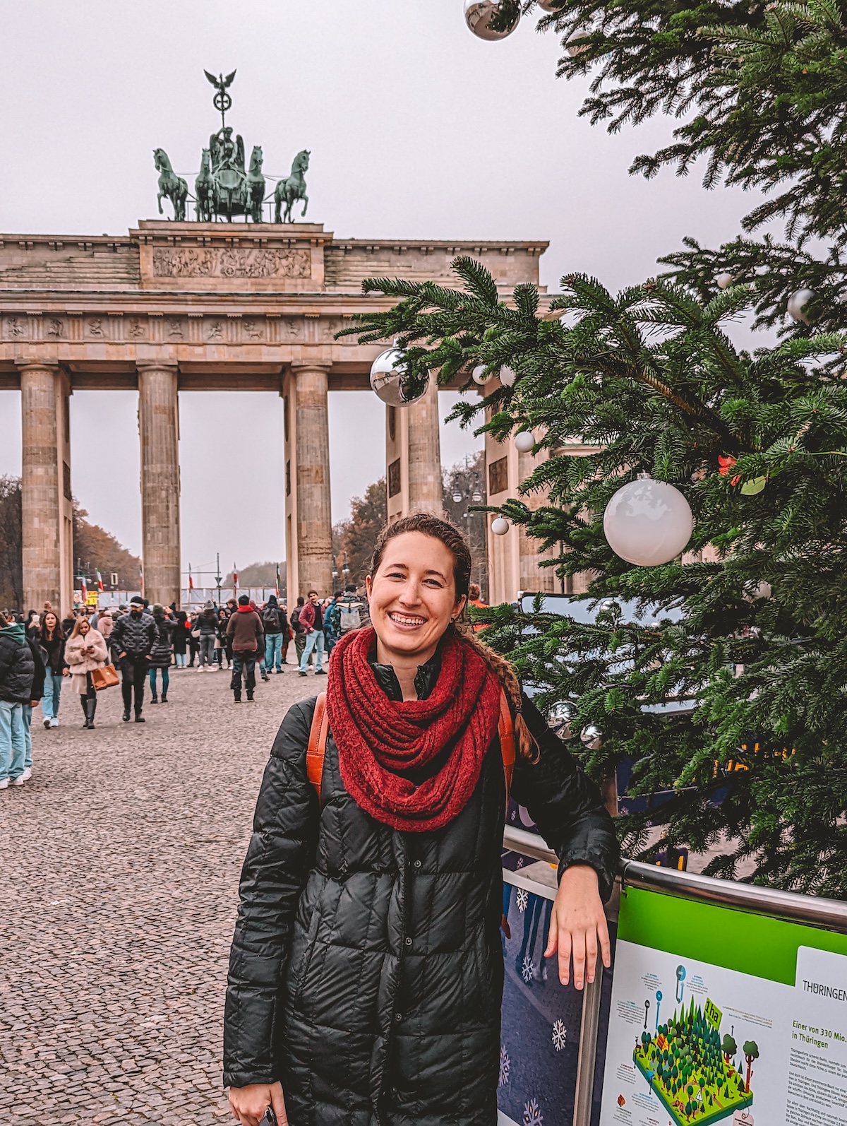 Woman smiling by Christmas tree in front of Brandenbug Gate