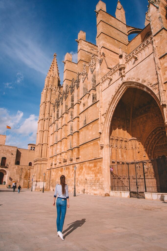 Woman facing the back side of the Cathedral of Mallorca.