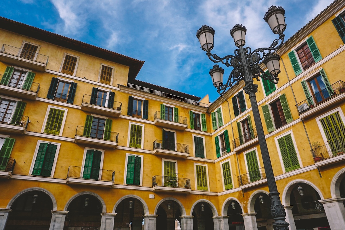 Looking up at the yellow arcades surrounding Placa Major in Palma. 