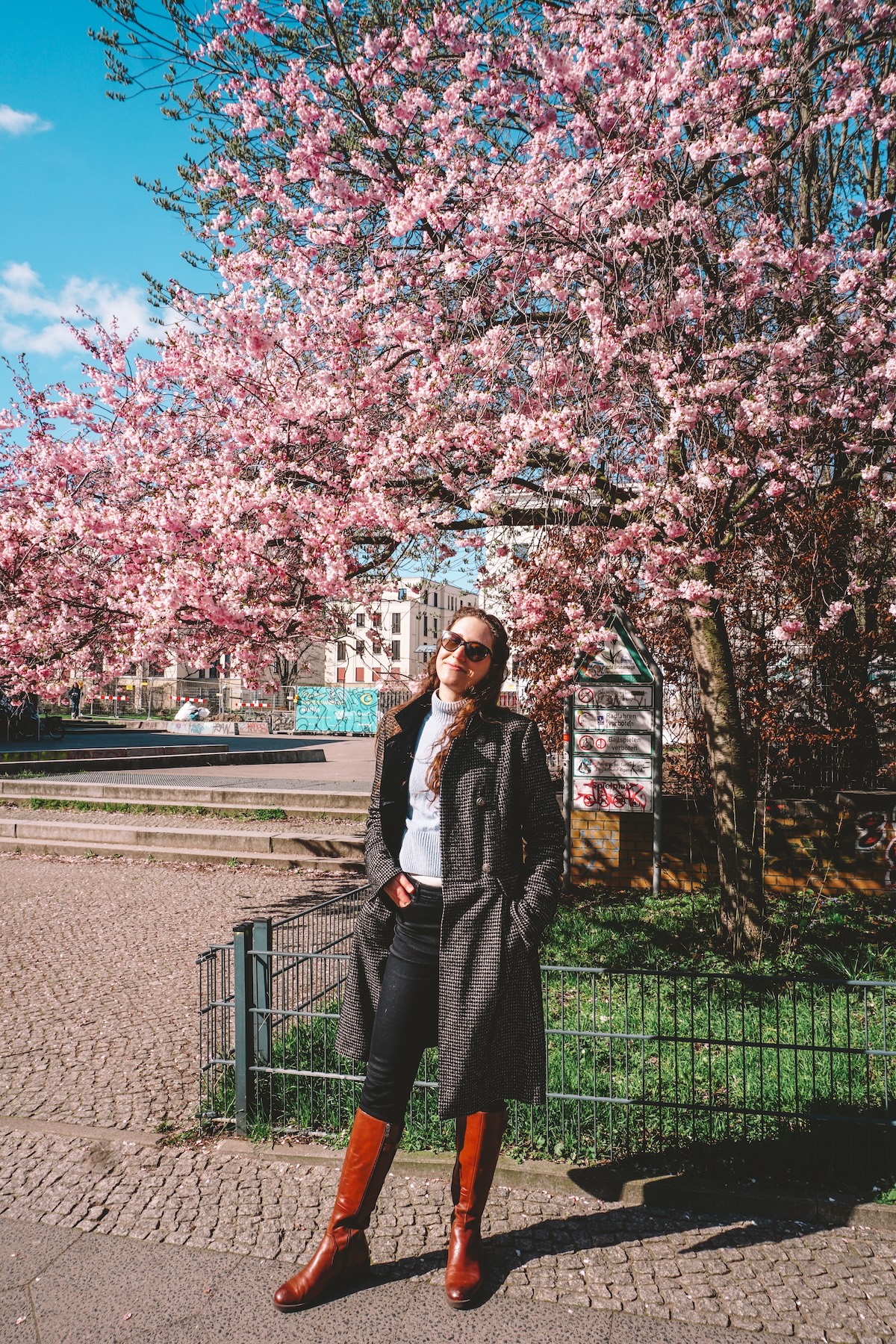 Woman smiling in front of cherry blossom tree