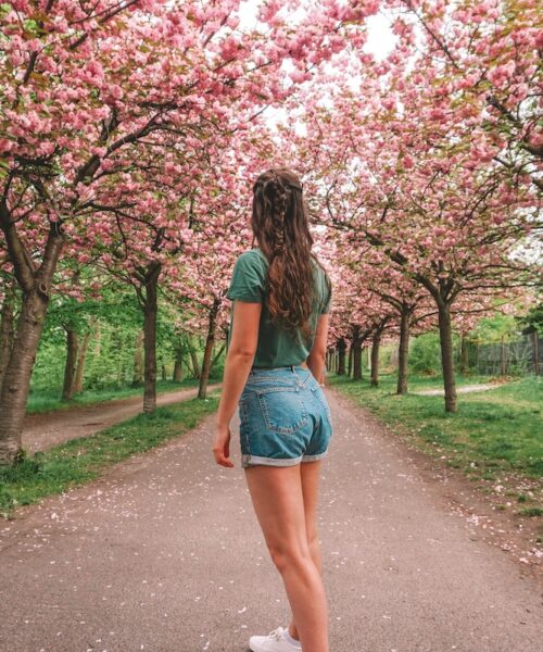 Woman looking behind her along a cherry blossom path
