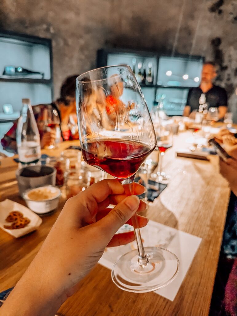 A glass of red wine held aloft at wine tasting